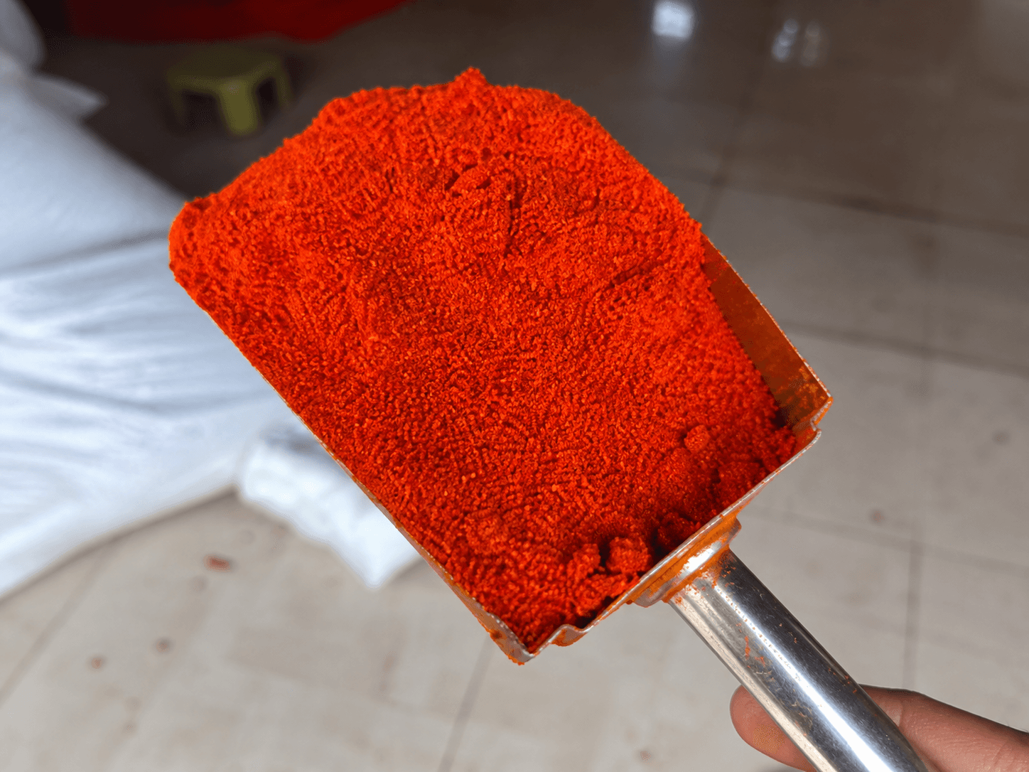 Deep red stemless chilli powder in a rectangular metal scoop